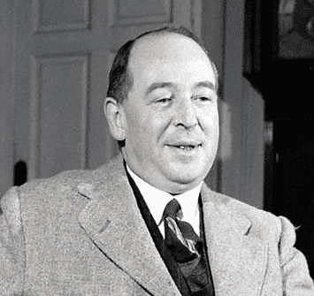 C.S. Lewis in a suit and tie sits indoors, smiling slightly. The background shows a door and part of a dark wooden cabinet or clock.